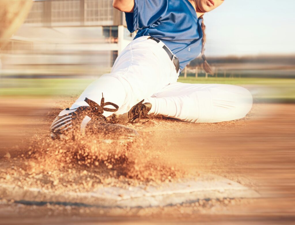 Slide, softball action and player in match or game for sports competition on a pitch in a stadium.
